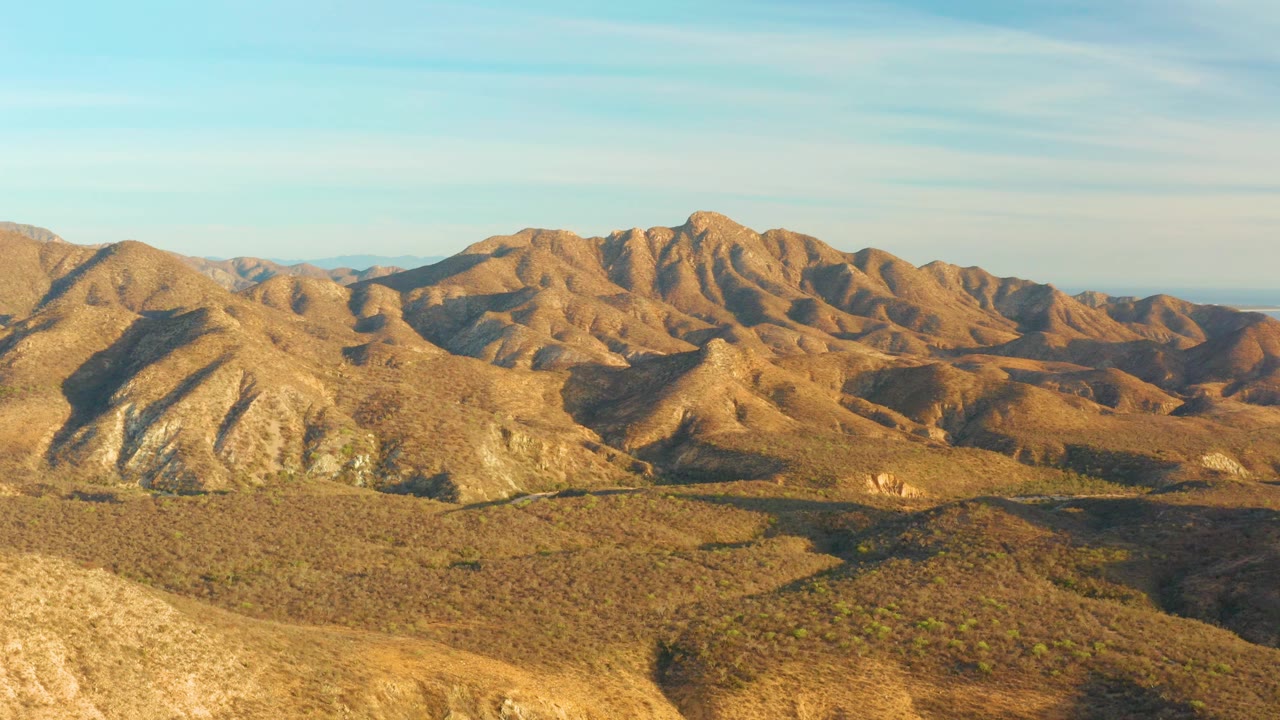 At 0:03, golden light covers the Cabo Pulmo ridges while darker slopes sit below the mountain range, with open sky above and no visible people.