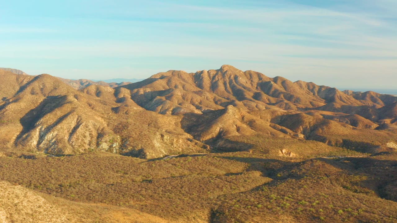 Aerial view of dry desert mountain ridges under blue sky