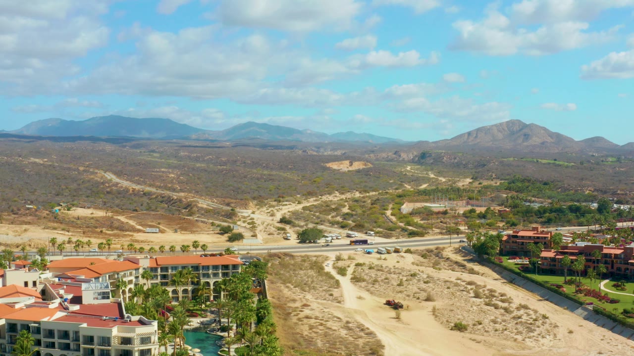 Aerial highway crossing dry landscape with red-roof buildings below
