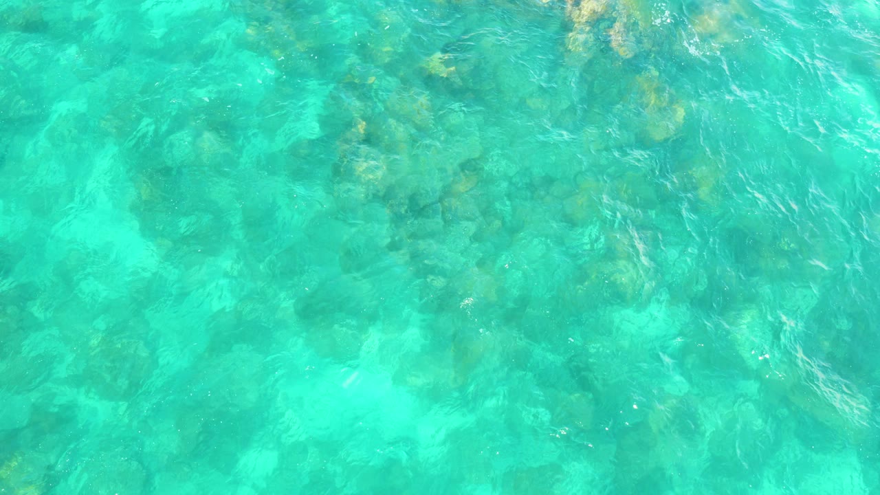 Top-down view of clear turquoise water over submerged rocks at Hilton Los Cabos, Mexico, with no visible people.