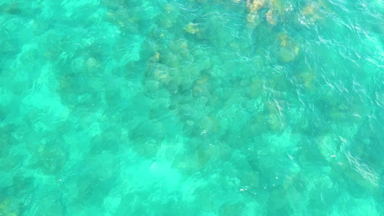Clear blue-green water with rocks below.