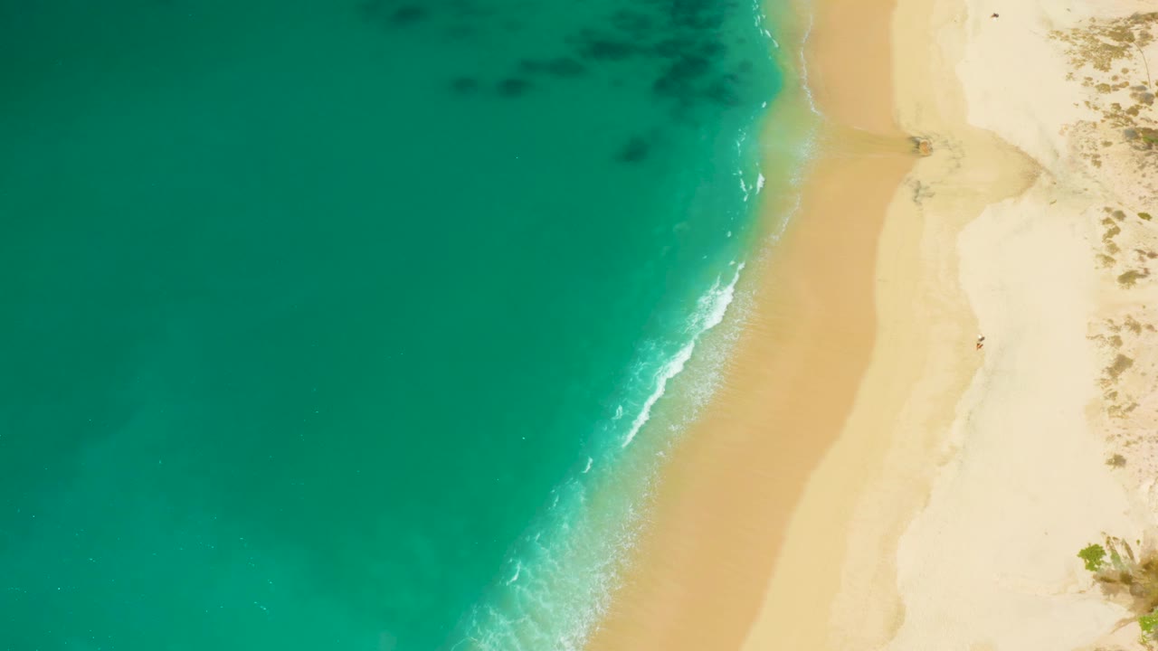 Turquoise water washing onto empty sand