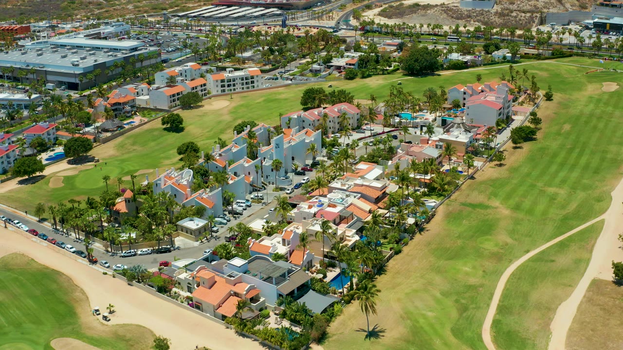 Drone view of red-roof buildings and golf course grass.