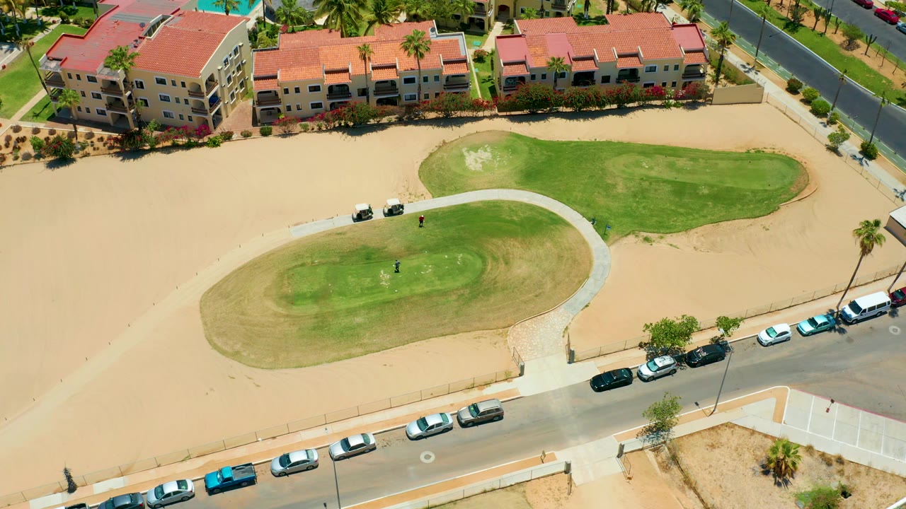 High-angle view of residential buildings, sandy open ground, and green lawn patches