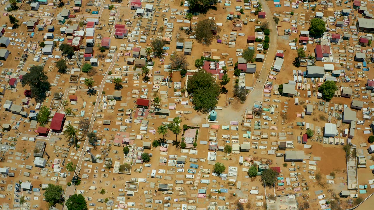 Top-down San Jose del Cabo view showing tightly spaced huts and houses around dusty open areas, with scattered green trees and no visible people.