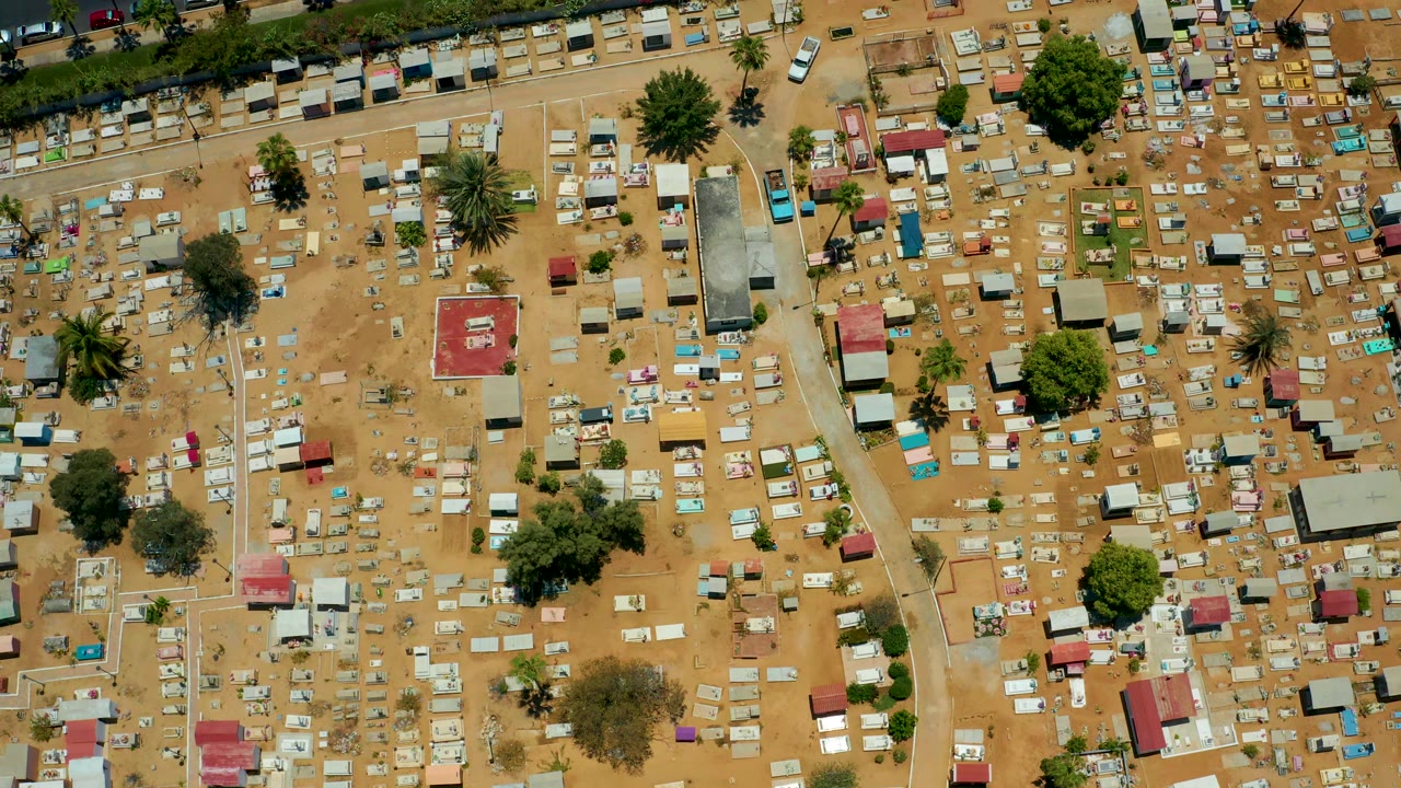 Aerial cemetery grid with many tombs, trees, paths, and small roofed structures.