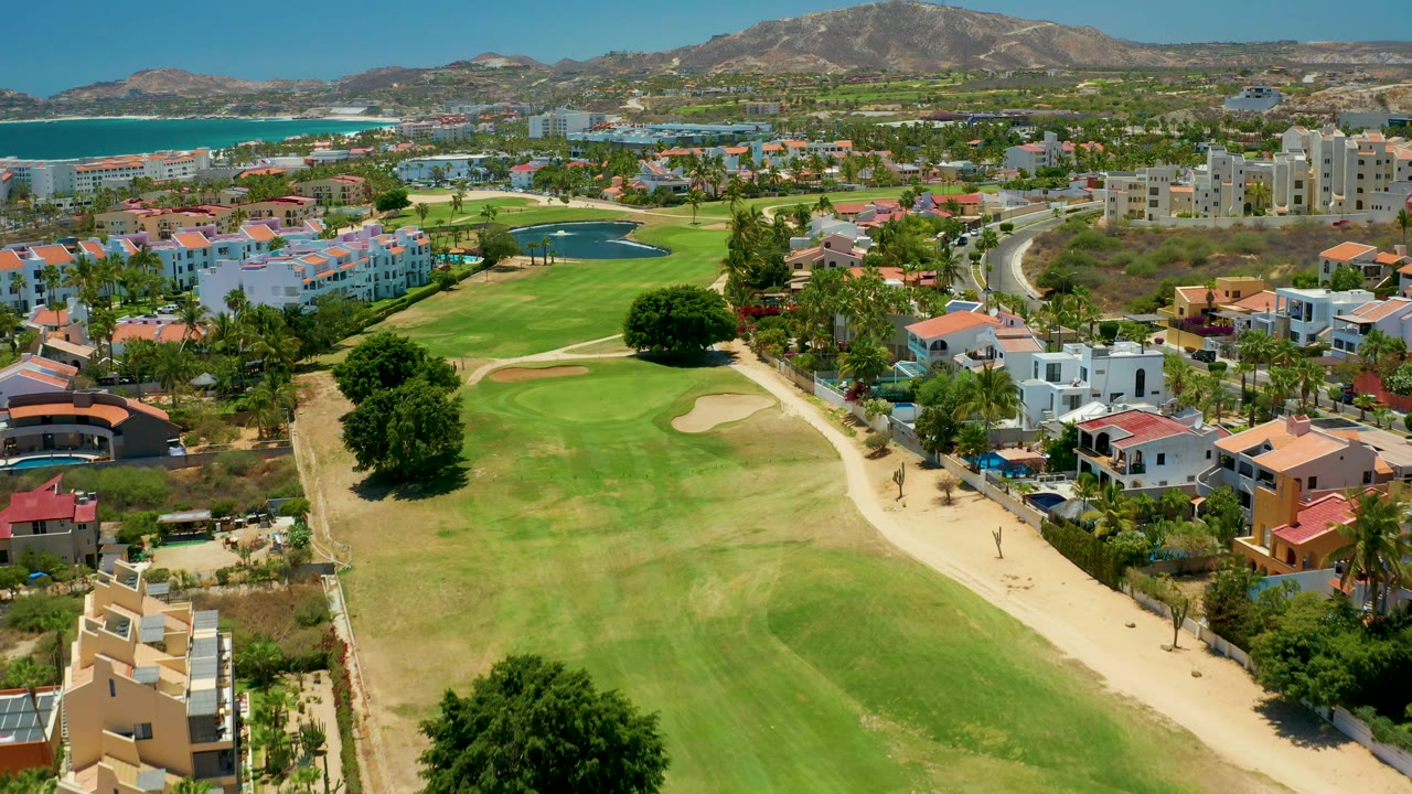 Aerial golf course with road curving through coastal neighborhood