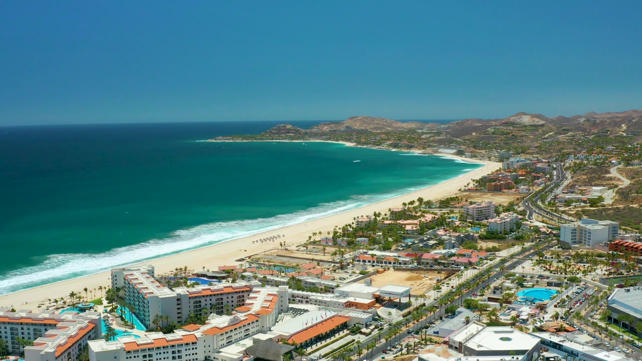 Drone aerial of coastline with road traffic and resort buildings