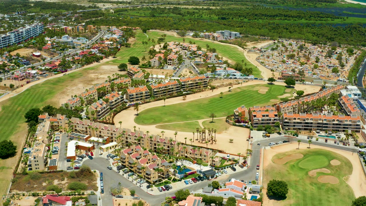 High aerial view across homes, parking lots, and a golf course.