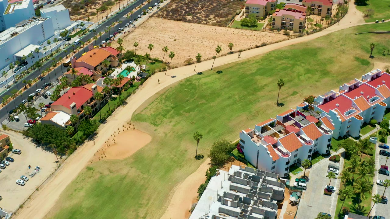 High aerial view of people walking on a dirt path beside grass and apartment buildings.
