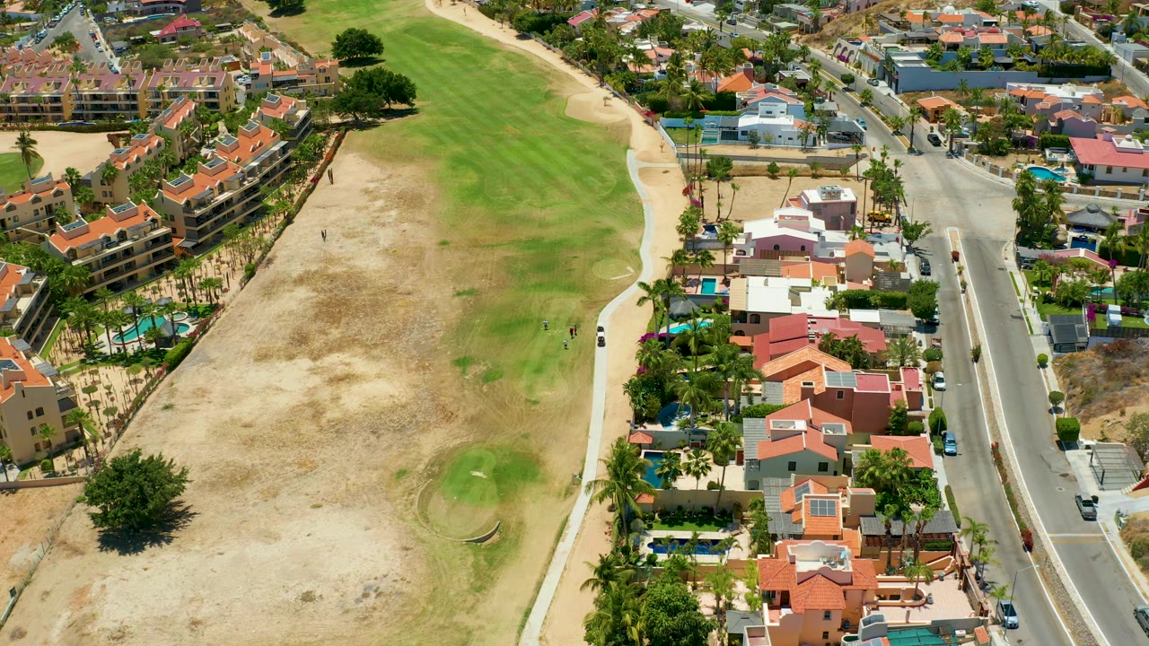 Golf fairway beside residential street and pools
