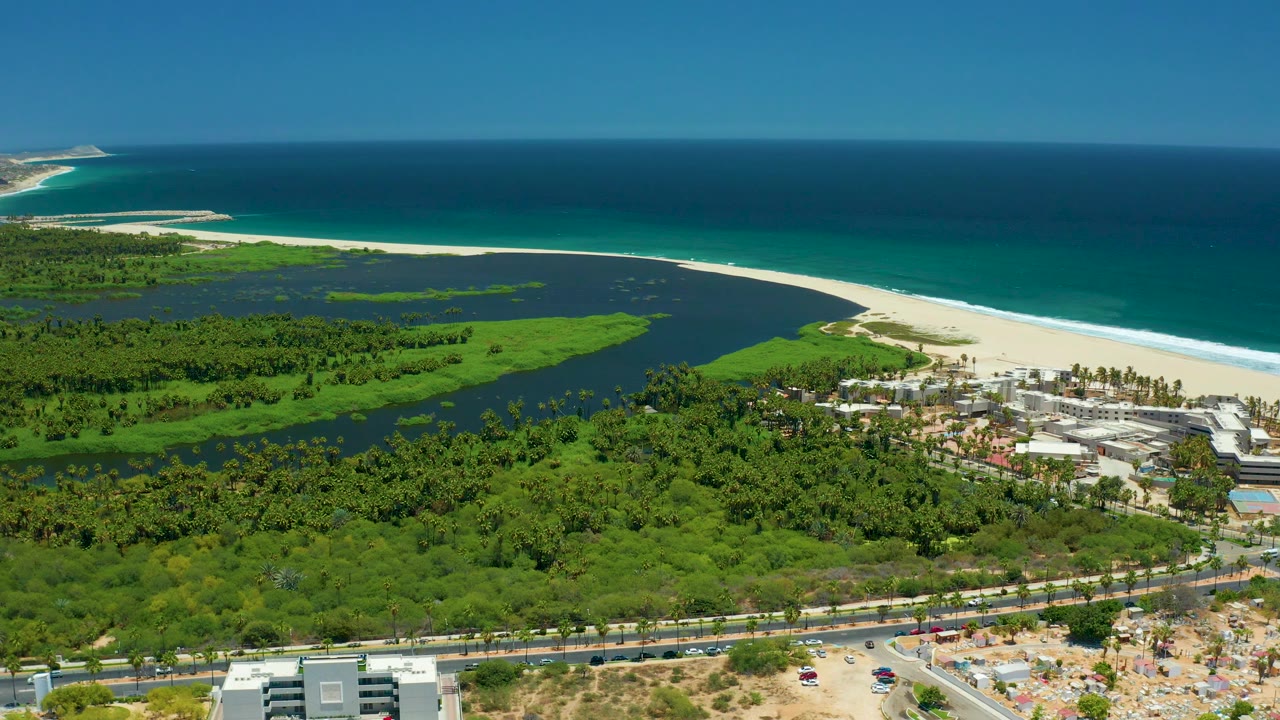 Lagoon and beach aerial with road and buildings in foreground.