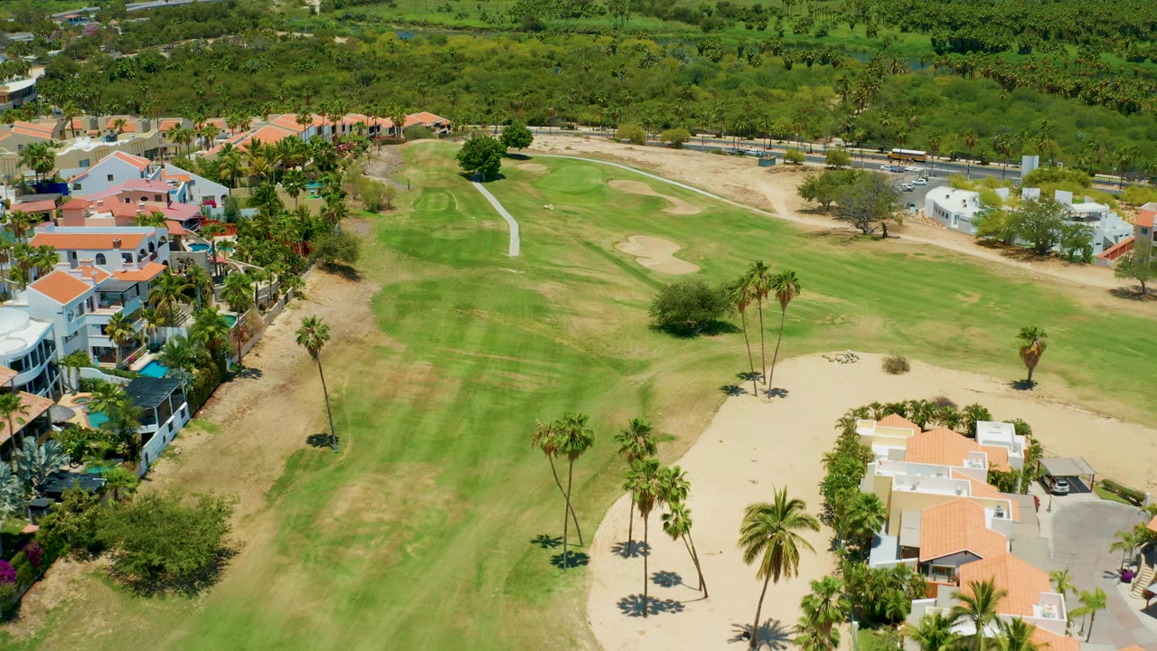 Drone view across fairways, sand traps, villas, and palms.