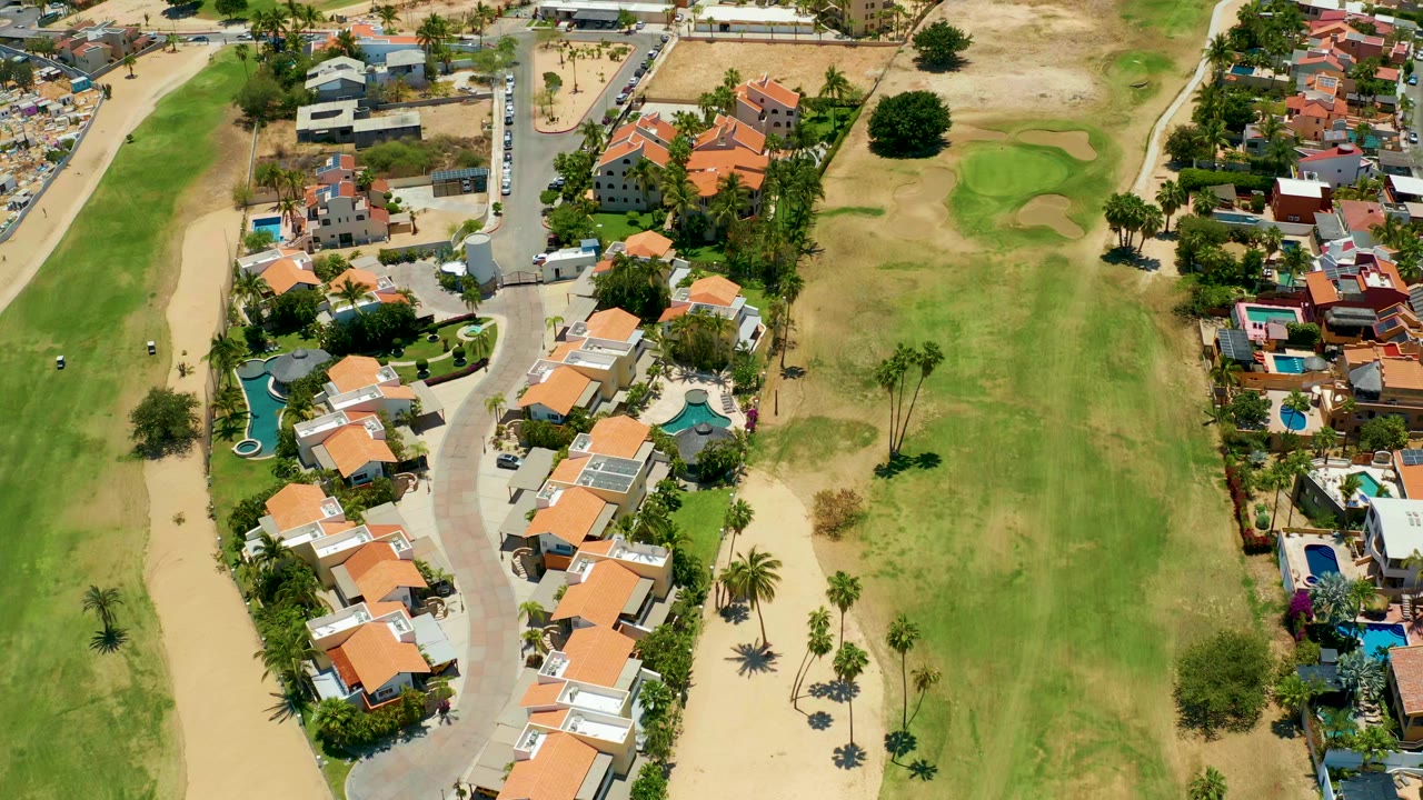 Aerial residential street with golf fairway and sand traps nearby.
