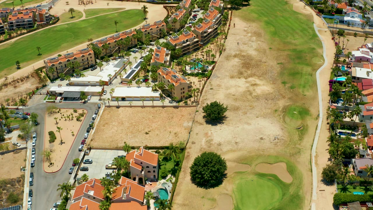 Overhead view of residential buildings, parking, roads, and golf course greens.