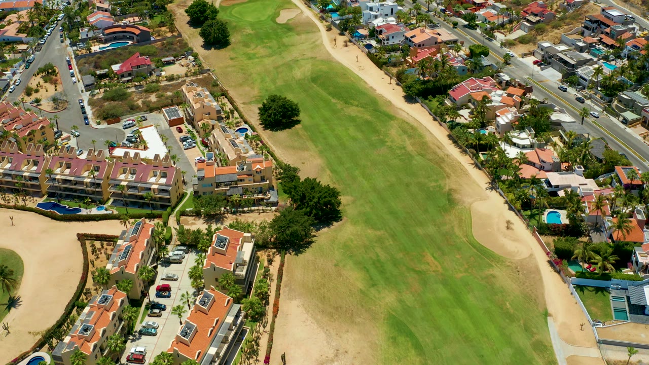 Residential neighborhood and road bordering a green golf course.