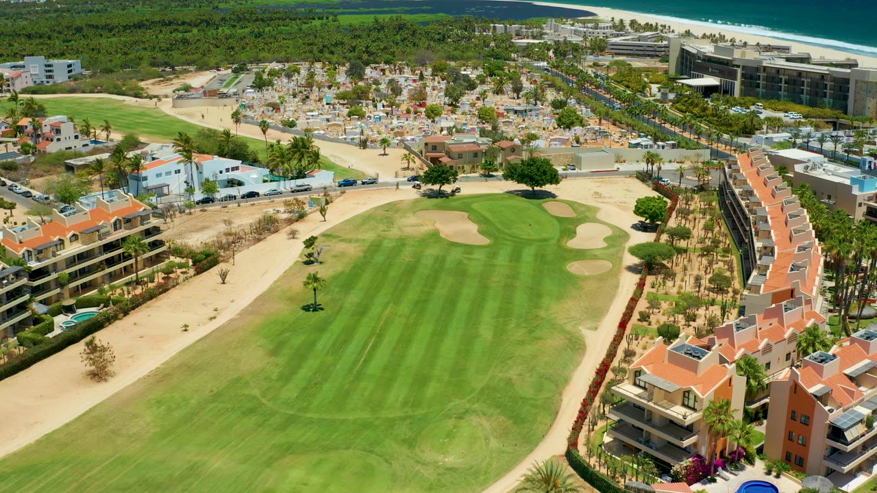 Aerial frame of a golf fairway beside red-roof buildings and desert landscaping
