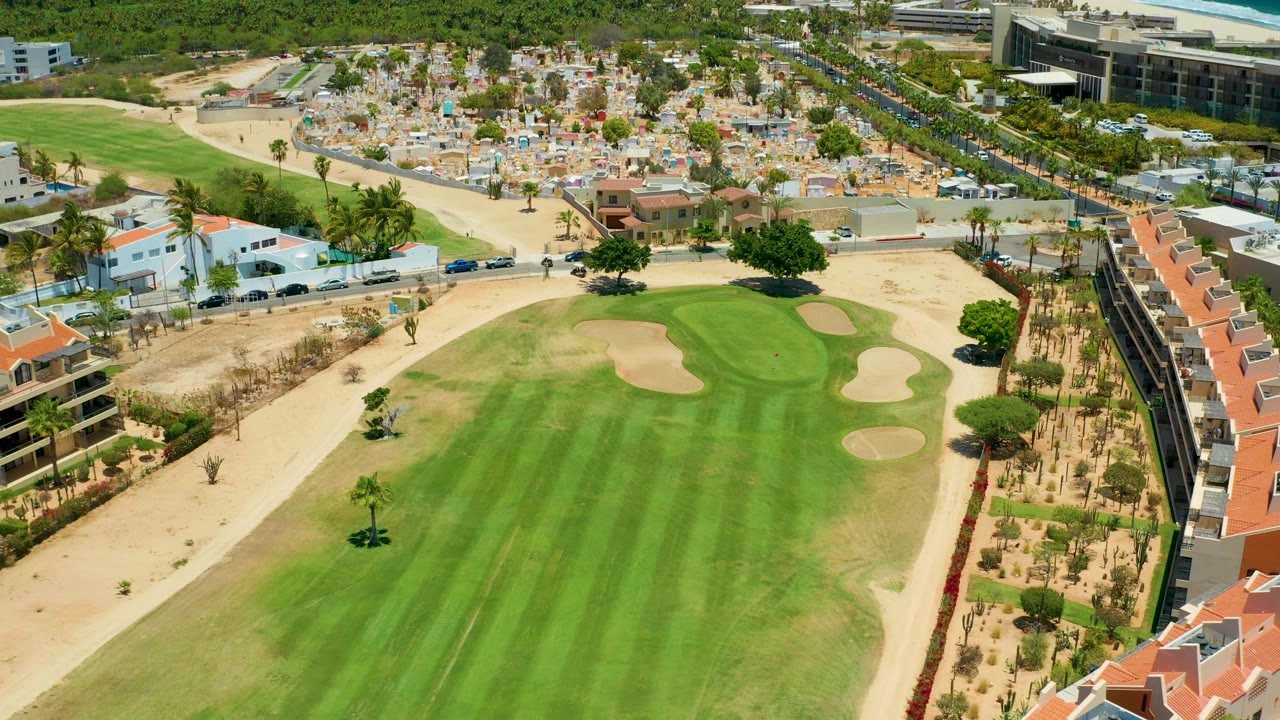 Elevated golf course view with green fairway, bunkers, roads, and homes.