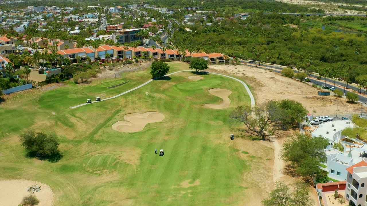 Golf cart on a green fairway near sand traps in an aerial view.