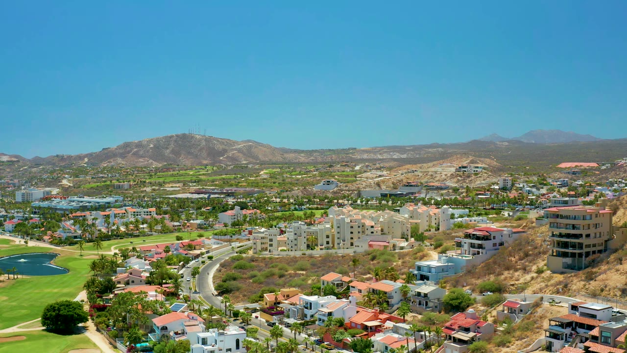 Residential roads and golf greens below distant hills
