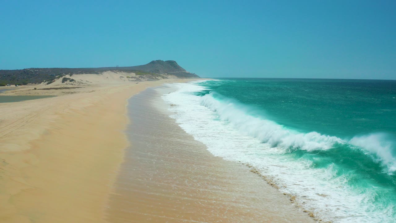 Aerial coastline with turquoise waves reaching a sandy beach