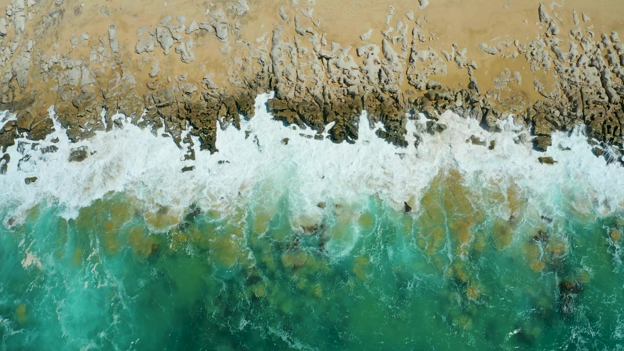 Dense white surf covering rocks near sand