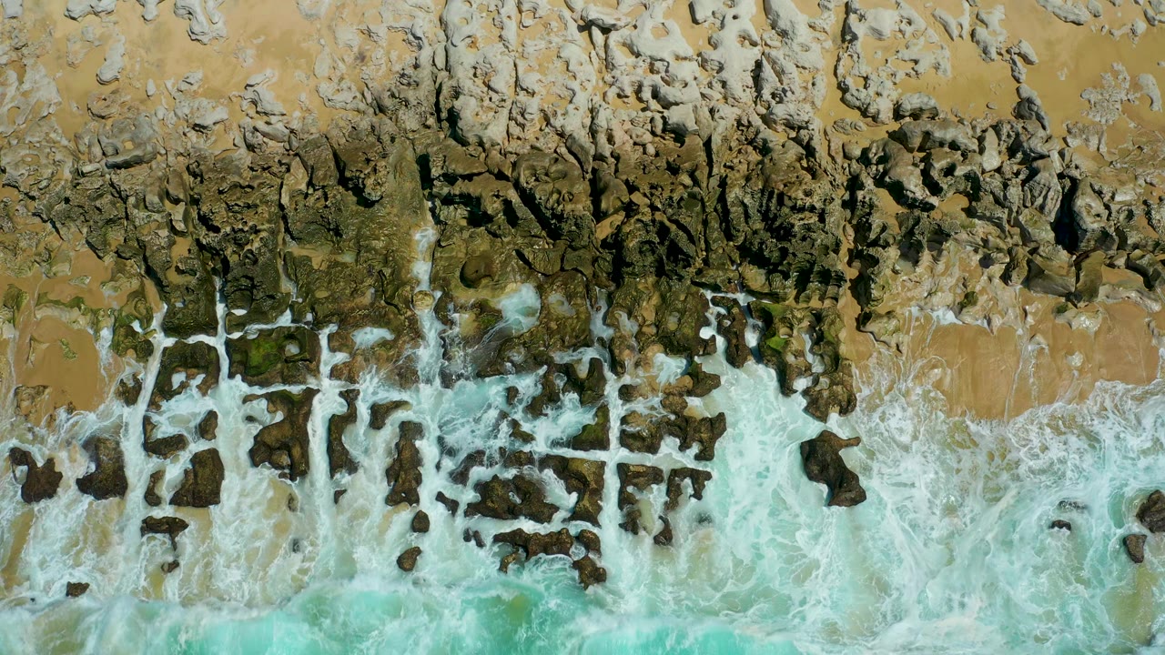 Foam crossing a dark rocky beach edge