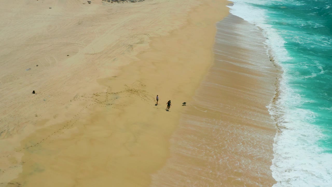 The La Laguna Beach shoreline curves down the right side as a small group continues along the sand, with one darker object or person separated to the left.