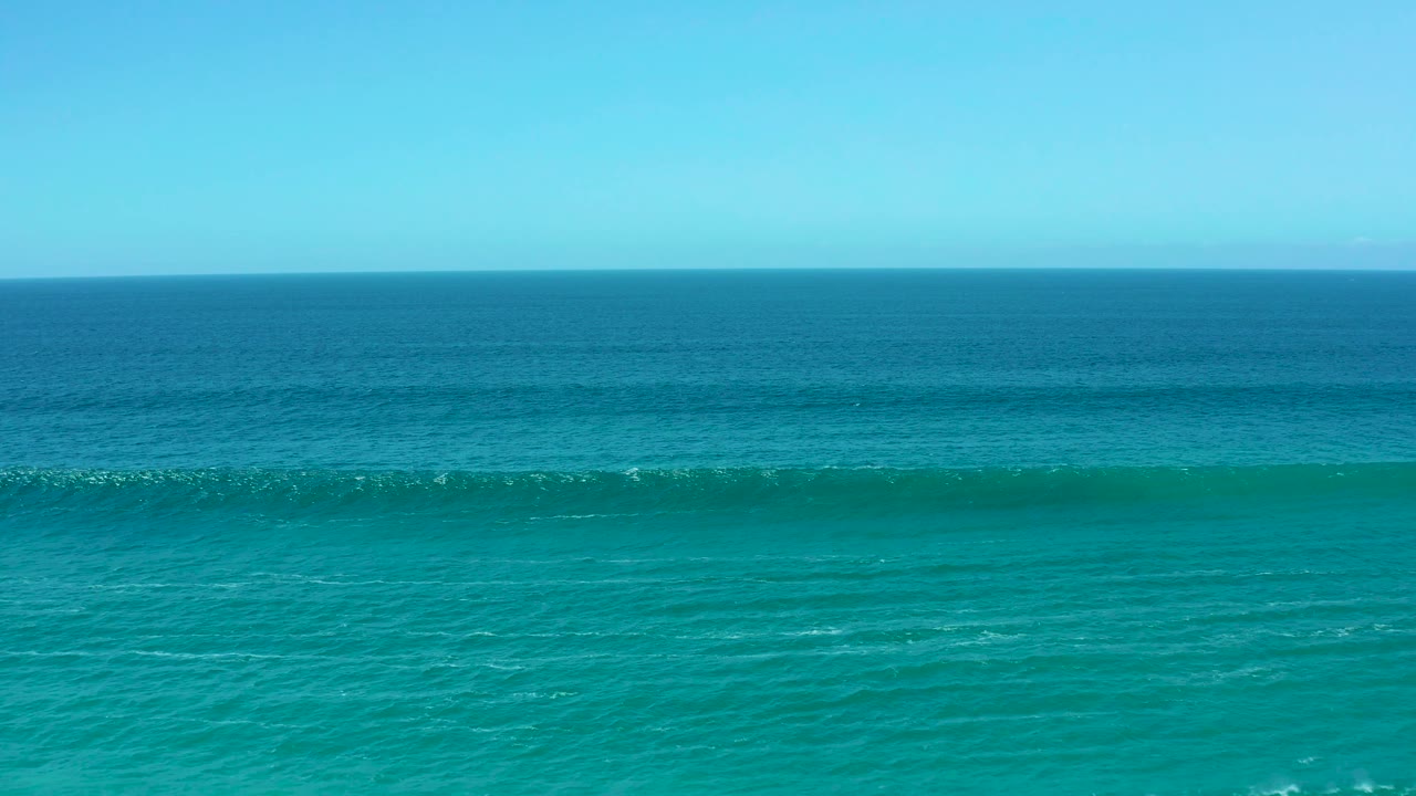 White foam appears along the breaking wave line on blue-green ocean water at La Laguna Beach Los Cabos, with no visible people or structures.