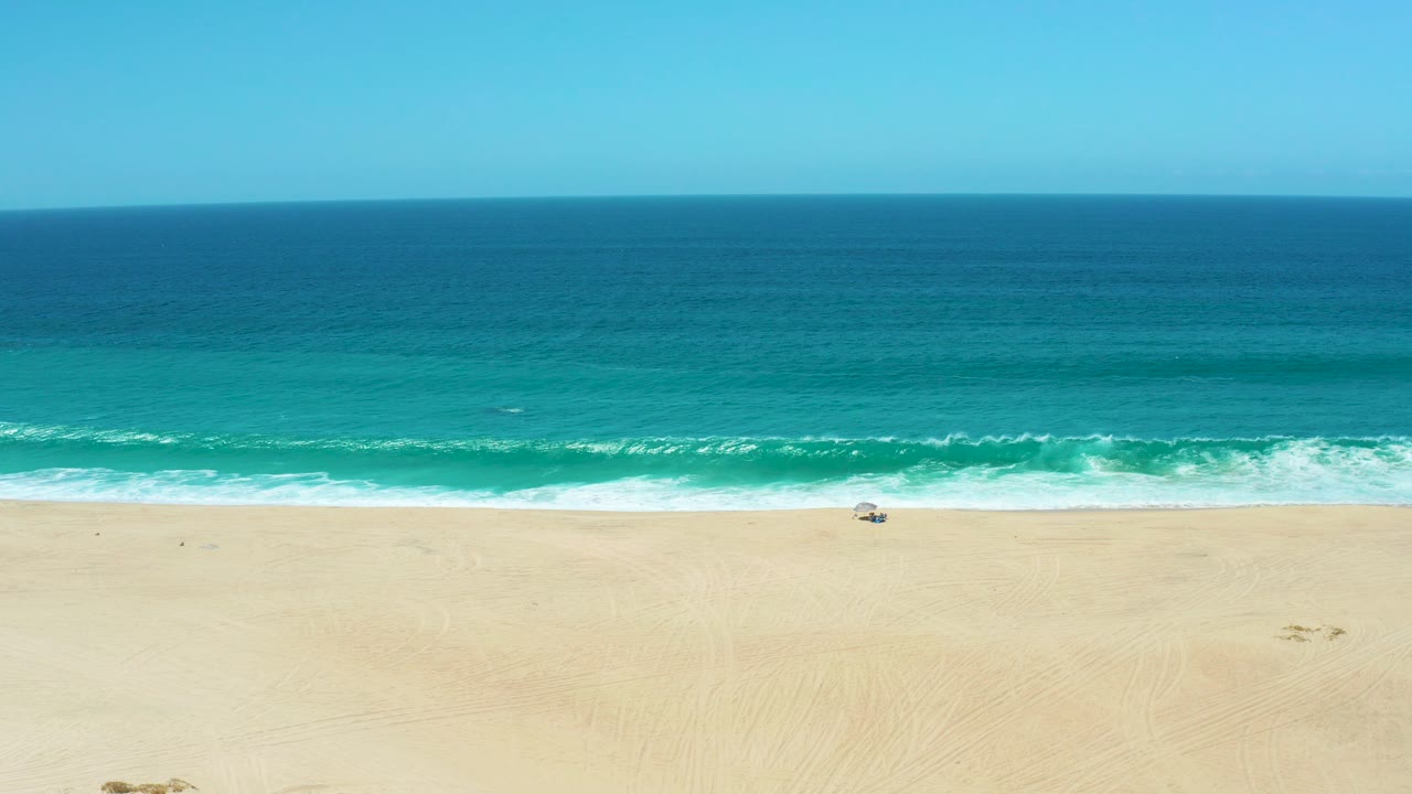 Open beach and ocean with surf foam spreading near the shore.