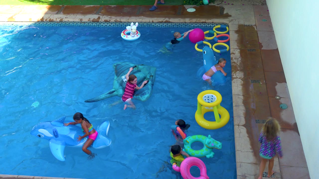 Children swim and climb on pool inflatables.