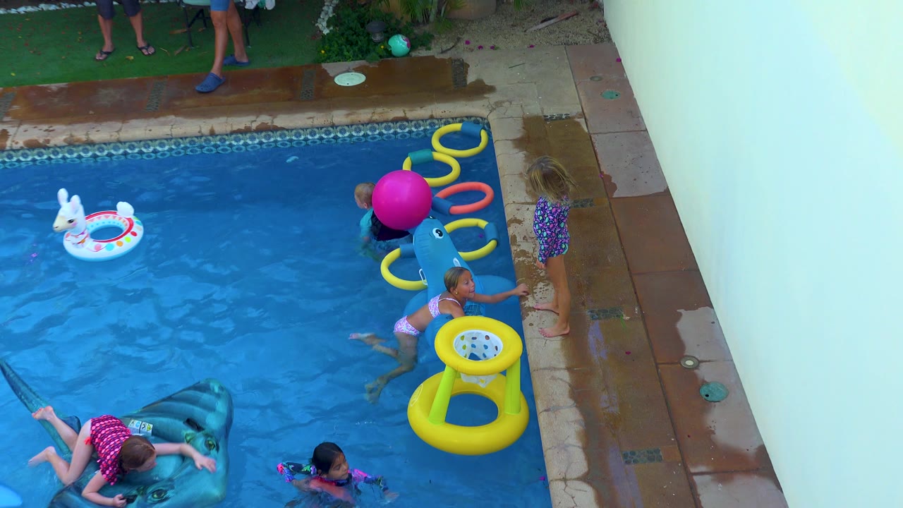 Children swim beside a whale float and pool rings.