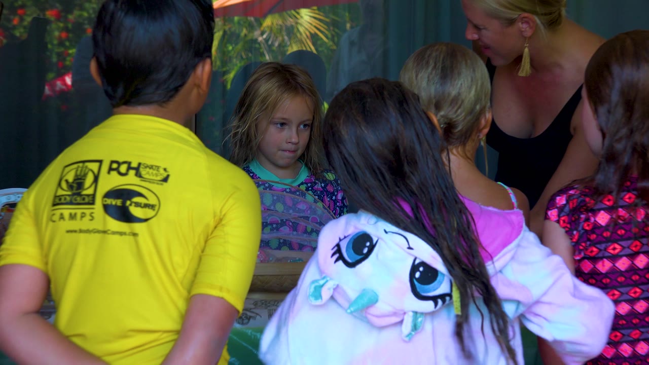 Closer view of children surrounding the birthday cake and candle.
