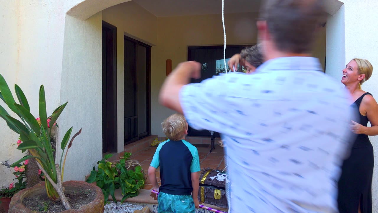 At 0:00 in San Jose del Cabo, adults and a blond child stand on a tiled patio while a man in a white shirt moves across the foreground and a woman in black laughs near the doorway.