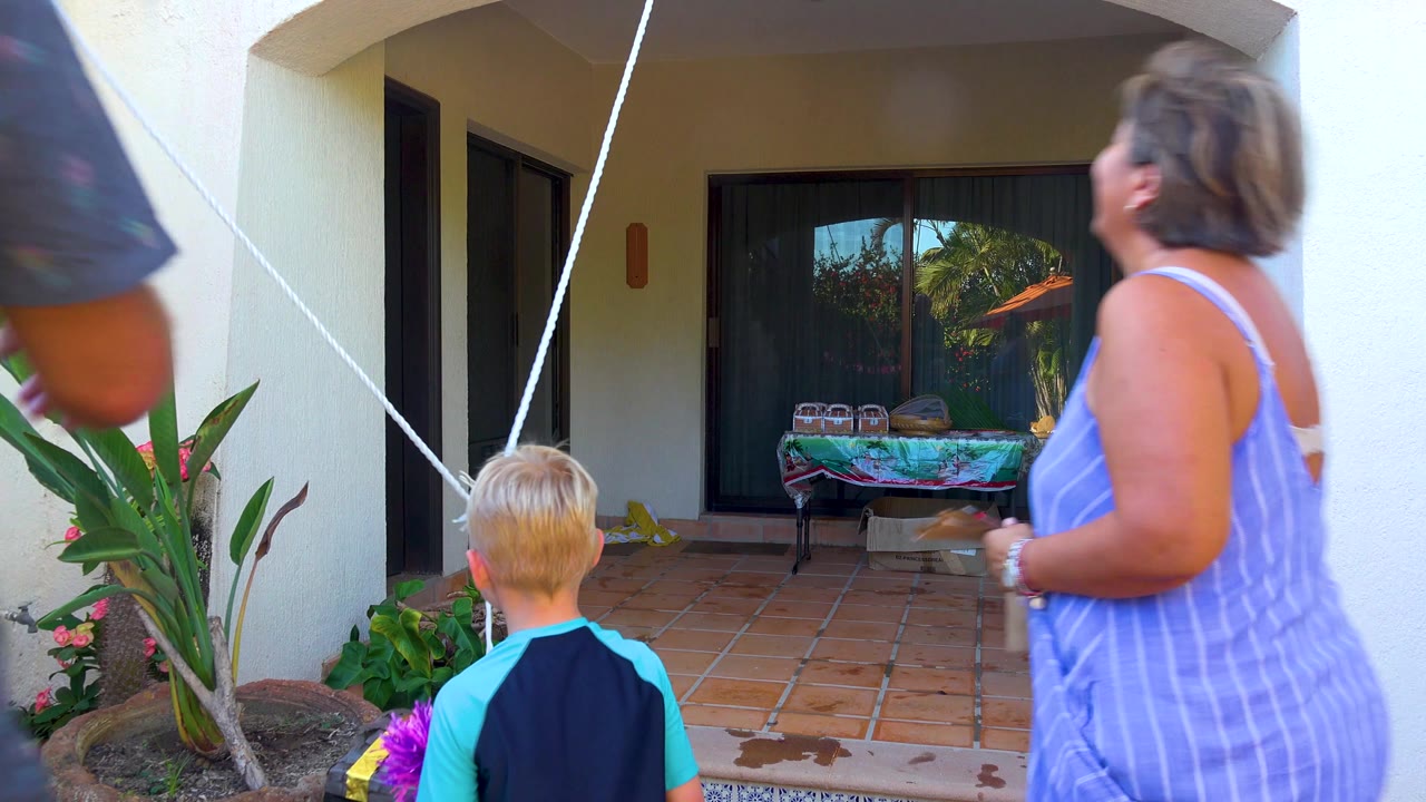 Man passes in front of the patio while a woman and child stand near the rope.