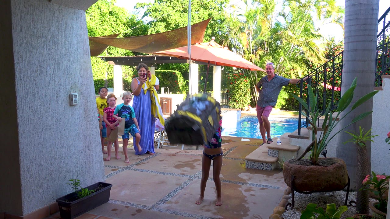Large tire swing moves across the patio while family members watch by the pool.