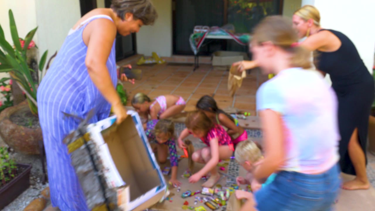 Children pick up treats while adults stand and bend nearby.