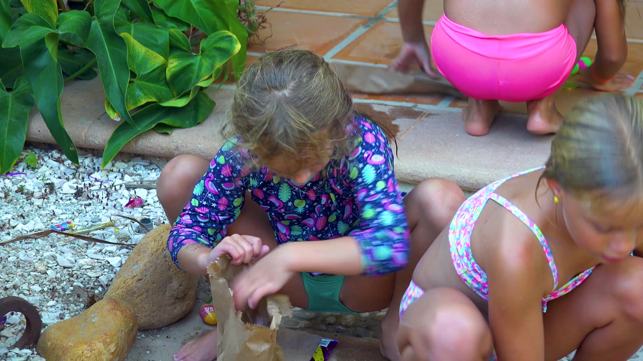 A child reaches toward a paper bag while another child moves through the foreground.