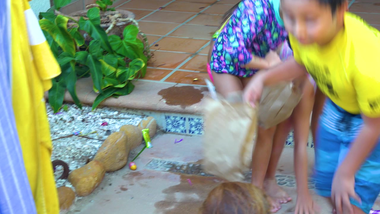 A child reaches near a paper bag on the patio.