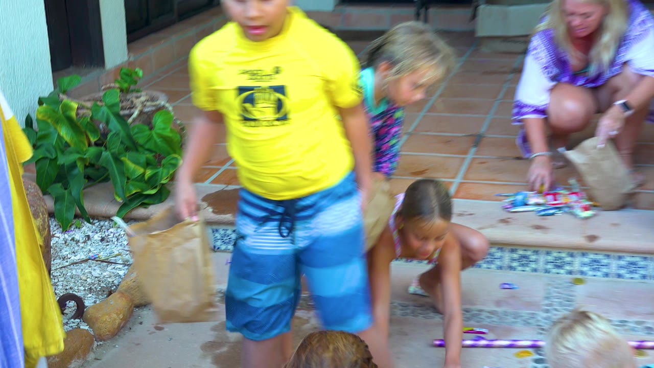 Children gather around small colorful items on a tiled patio while a woman kneels near the steps in San Jose Del Cabo.