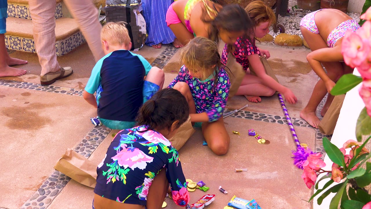 Kids crouch around colorful treats on a wet patio.