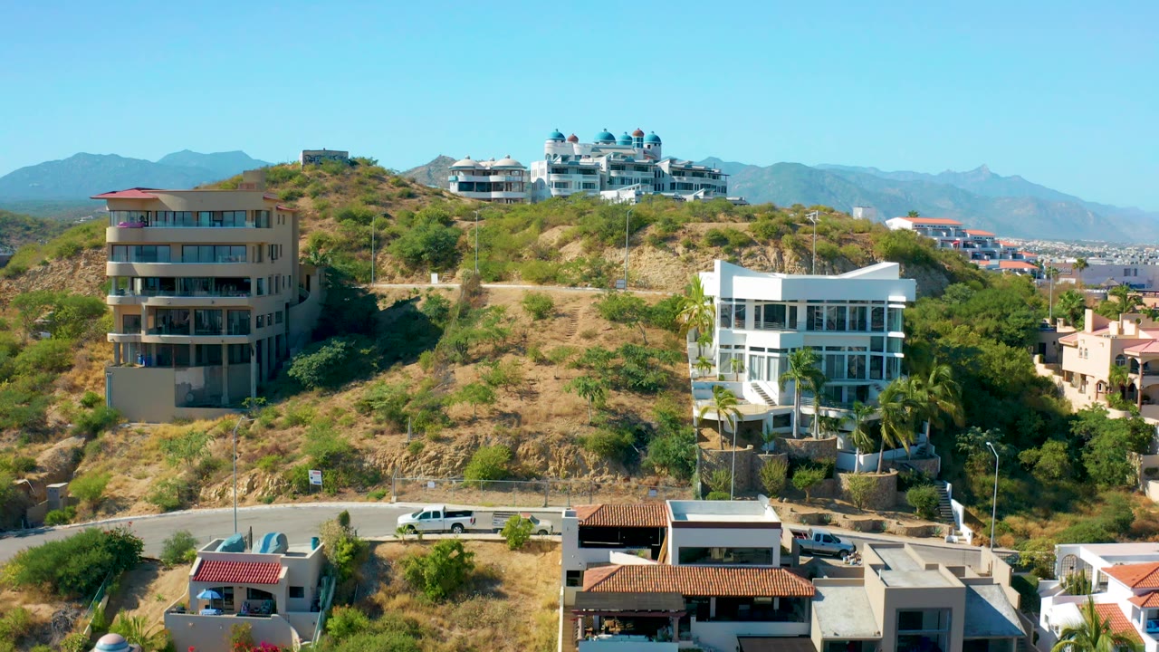 Hillside residential buildings above a road with a white vehicle
