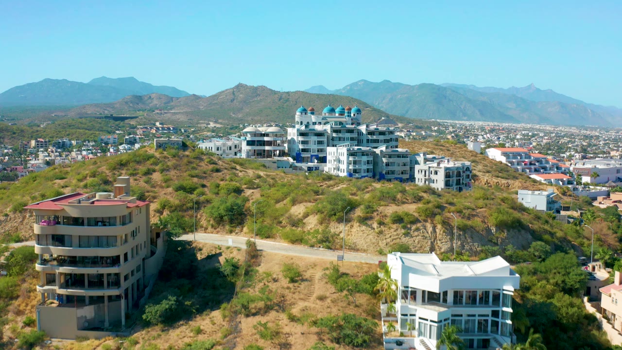 Aerial view of hillside residences with town and mountains beyond.