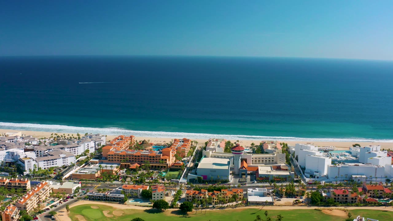 High aerial view of San Jose Del Cabo beachfront resort area and ocean under clear sky.