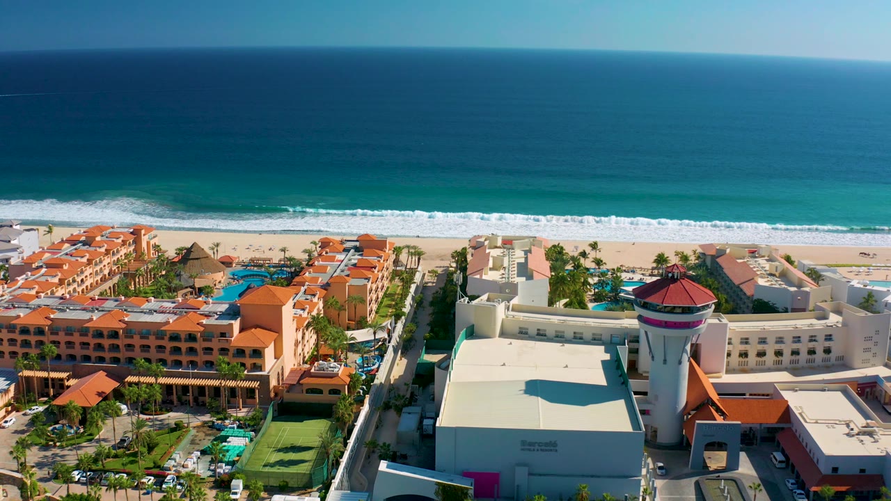 Aerial resort view with ocean horizon, beach, and red roofs.