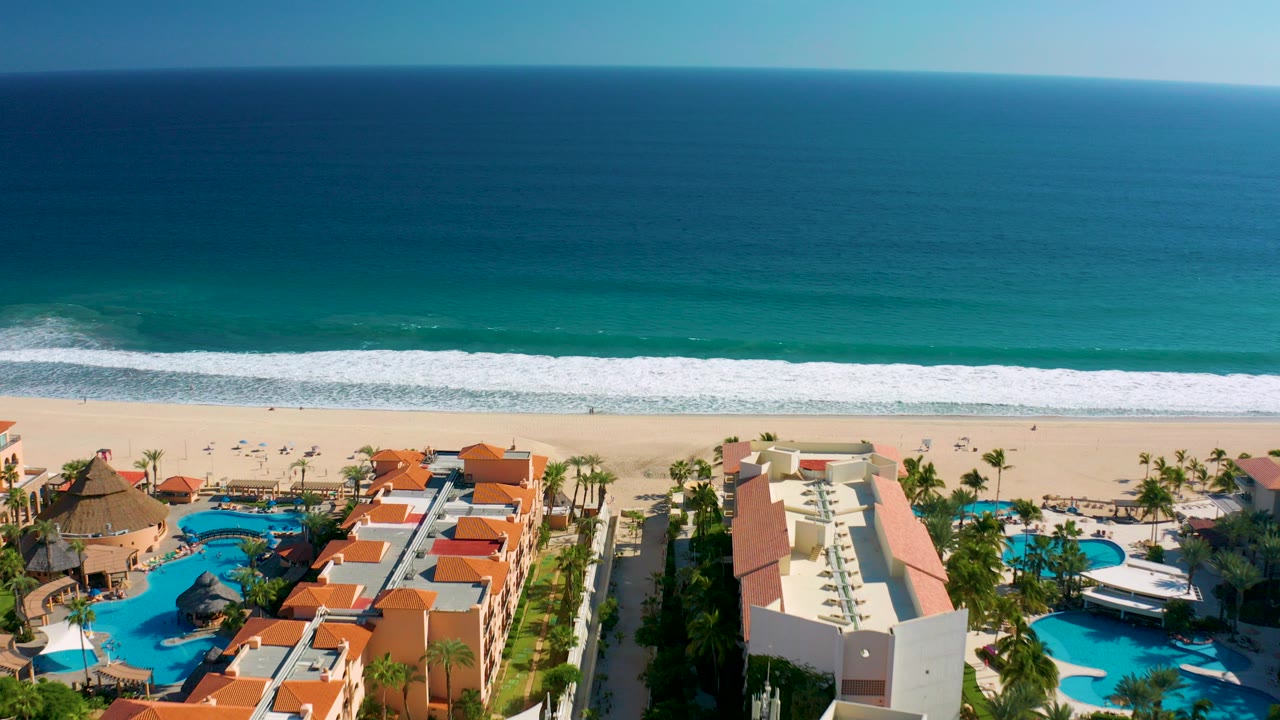 Aerial view of beach resort pools beside a wide ocean shoreline