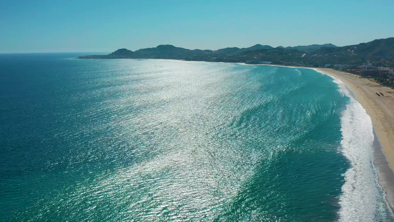 Reflective ocean water beside an empty sandy coast