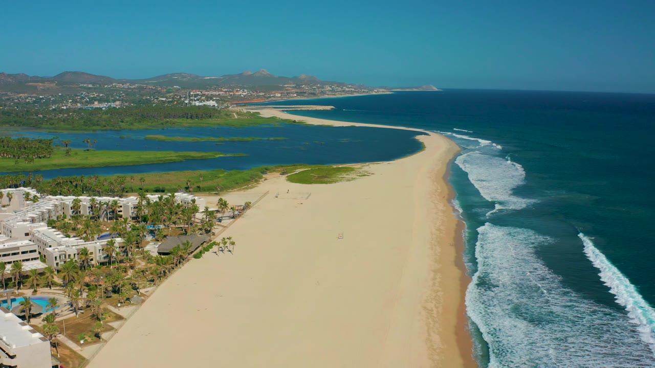 Beach and surf viewed from above with lagoon and buildings nearby