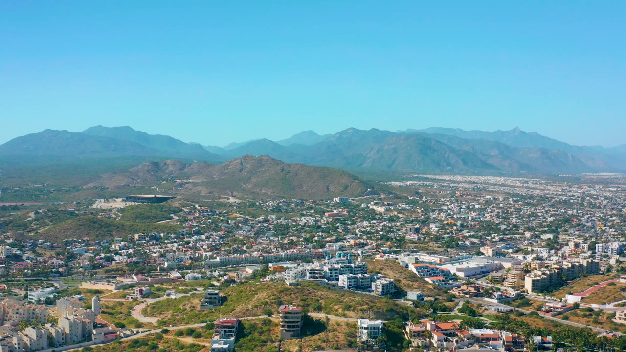 Cityscape below a clear sky with mountains across the horizon.