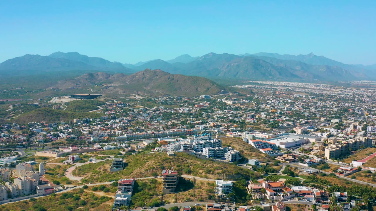 Wide city panorama with foreground hills and distant mountains